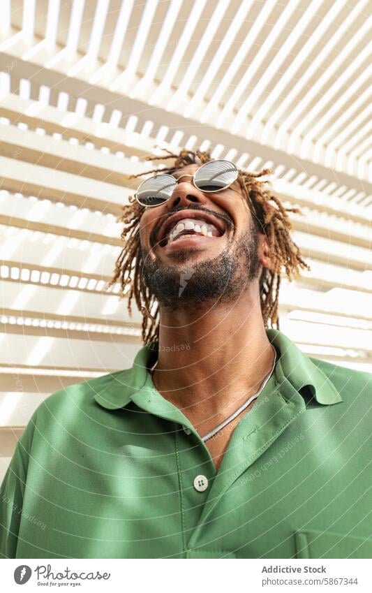 Joyful African American man smiling in summer sunlight african american joyful sunglasses dreadlocks laughing green shirt stylish outdoor sunlit happiness