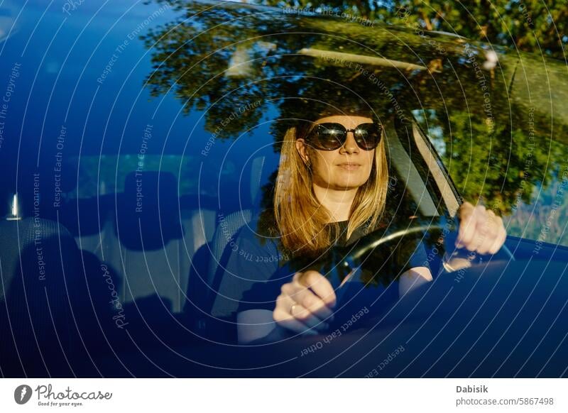 Happy woman is sitting in car. View through windshield driver enjoy happy female driving vehicle attentive travel adult attractive beautiful caucasian owner