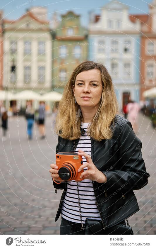 Female traveler taking picture with vintage instant camera tourist photo woman tourism photography memories trip scenic daytime capture orange retro nostalgia