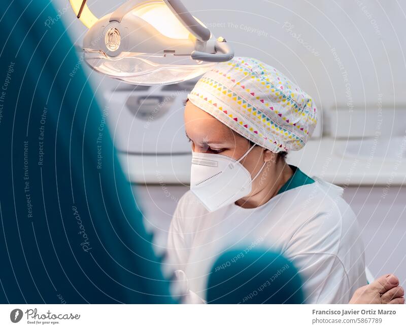 Female podiatrist doing chiropody in her podiatry clinic. Selective focus woman nail callus foot patient pedicure medicine bunion chiropodist health doctor care