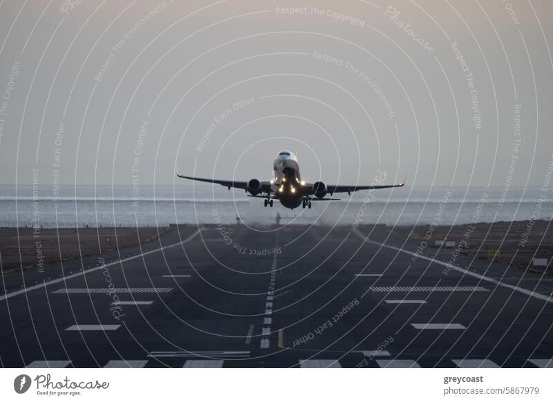 Airplane taking off from runway at dusk airplane takeoff aircraft ocean lights sky travel transportation flight aviation airport evening ascent jet departure