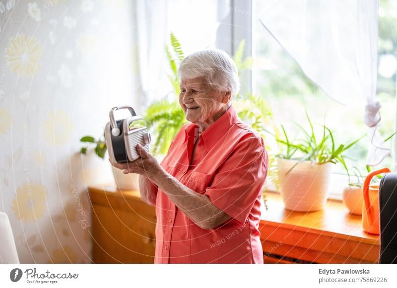 Smiling elderly woman listening to the radio at home smiling happy enjoying positive contented people senior mature female house old aging domestic life