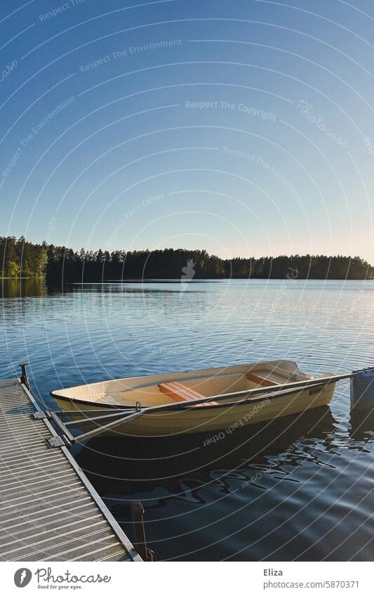 Small rowing boat moored at a jetty on a lake Rowboat Lake bank Nature Blue sky sunshine Idyll Landscape Water Calm Lakeside trees Forest Paddle Deserted