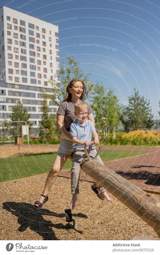 Mother and young son enjoying a seesaw ride in park mother summer smiling family play outdoor sunny leisure parenting woman boy child activity recreation fun