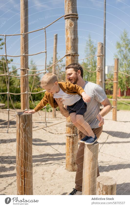 Father helping son navigate wooden play structures at park family summer father playground interaction support balance fun playtime child parent male outdoor