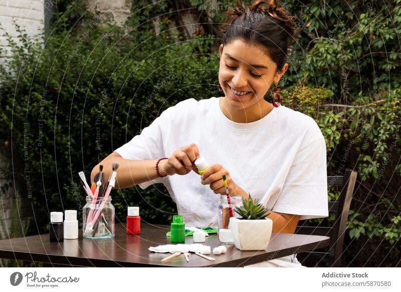 Woman enjoys painting clay crafts in a garden setting woman outdoor table creative hobby artistic decoration serene vibrant plant process smile colorful