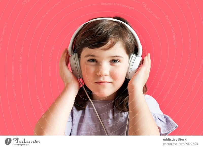 Young girl wearing headphones on a red background kid studio music technology child listening sound audio gadget device portrait cute young leisure indoor