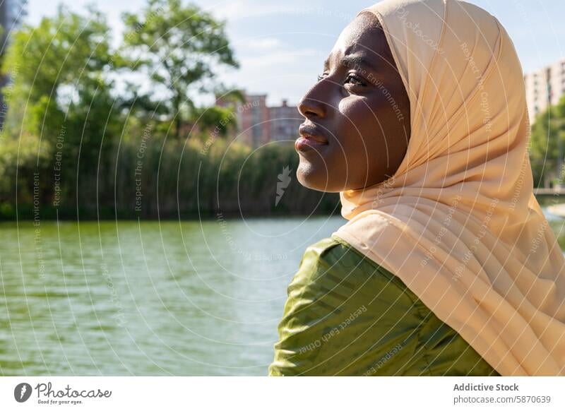 Woman in Hijab Enjoying a Sunny Day by the Lake park family hijab outdoors day tranquil moment serene water trees relaxation peaceful bonding woman leisure