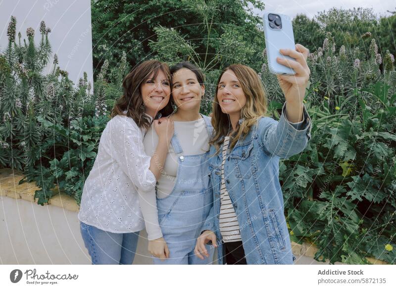 Three women taking a selfie together in a garden smartphone camera smile friendship adult female greenery joy cheerful technology togetherness leisure casual