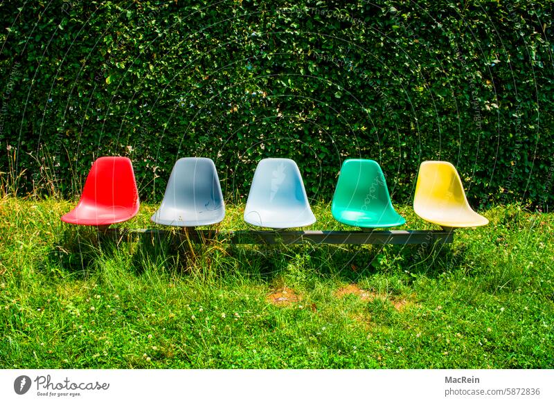 Five designer chairs in a garden seats Row of seats colored Exterior shot Deserted nobody