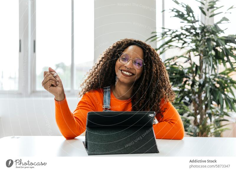 African American woman smiling at camera in coworking space african american tablet modern office plant device gadget mobile phone indoor professional cheerful