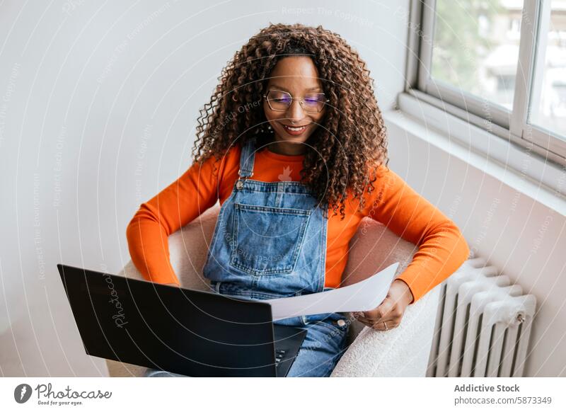 African American woman working on laptop in cozy setting african american document casual coworking technology gadget device comfortable relaxed orange shirt