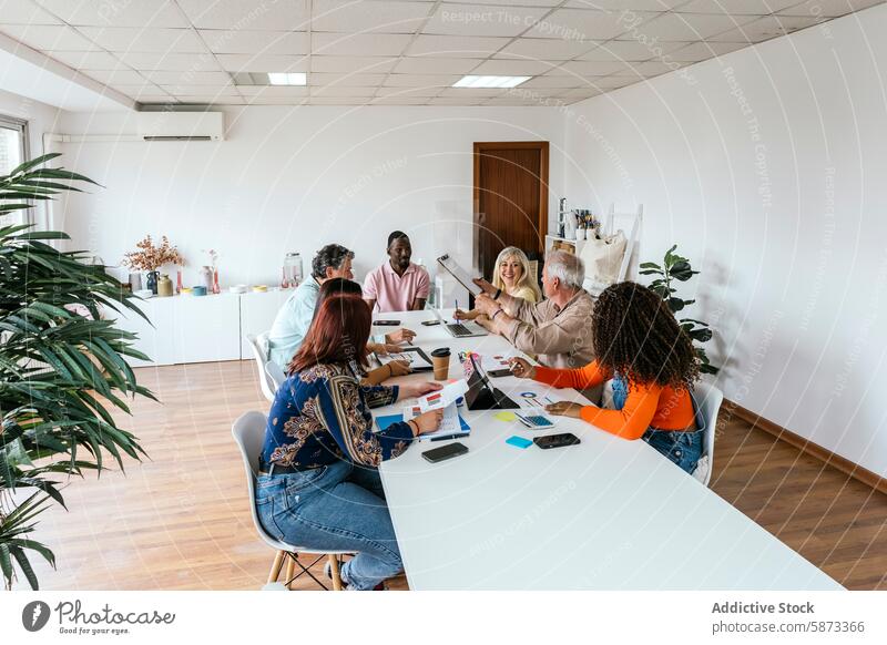 Diverse team collaborating in a modern coworking space collaboration office meeting business technology gadget device mobile phone discussion table chair indoor