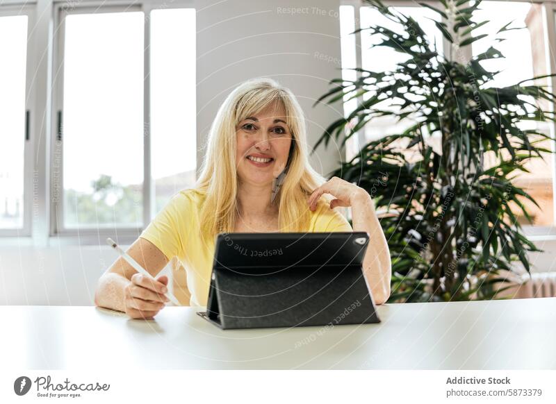 Businesswoman using a tablet in a bright coworking space businesswoman office indoor plant technology device gadget workspace professional smile caucasian