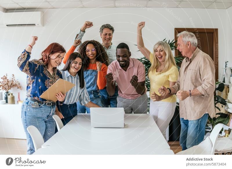 Diverse team celebrating success in coworking space celebration laptop enthusiasm teamwork cheering multiethnic diverse multiracial men women meeting elderly