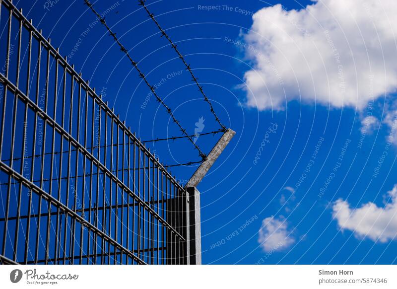 Metal fence with barbed wire in front of a slightly cloudy sky Metalware Barbed wire Fence Sky Barbed wire fence Border Barrier Captured Safety