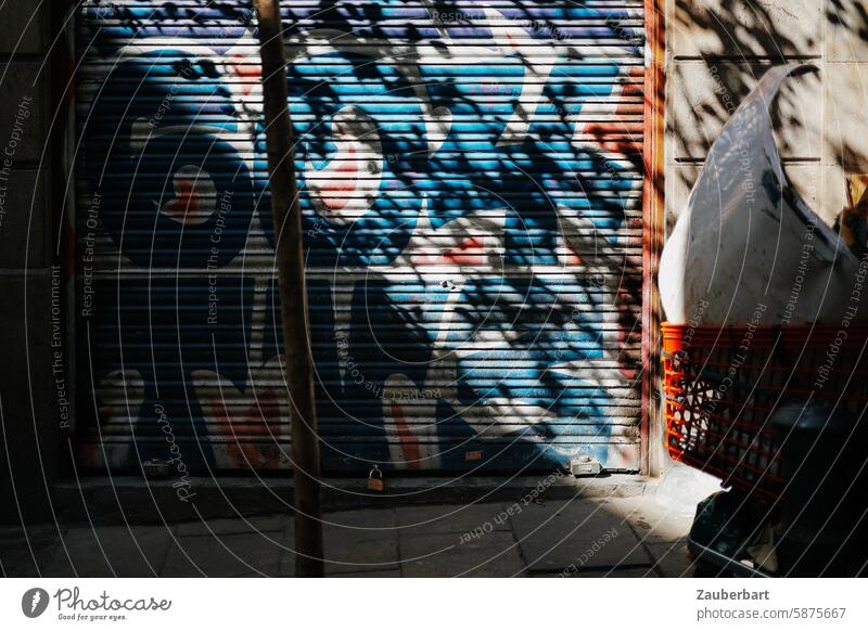 Leaves cast a confused shadow on a garage door with graffiti leaves Shadow mazy Graffiti variegated disordered Chaos Dynamic Wild Blue Red Light Sun obliquely