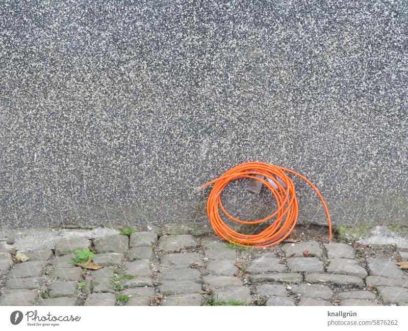 wired Cable Technology Energy stream Electricity Transmission lines house connection Facade house wall Paving stone Gray Orange coiled Connection Save energy