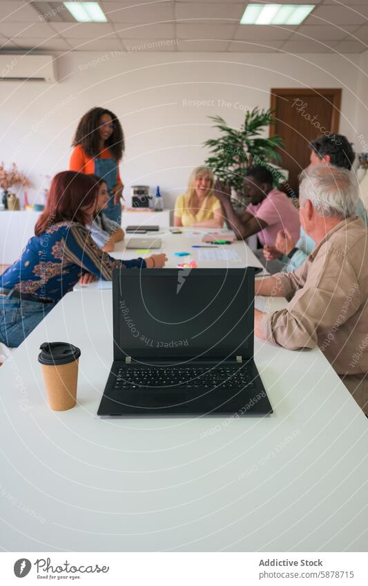 Diverse team collaborating in a modern office setting collaboration discussion professional diverse laptop coffee cup table meeting group indoor business