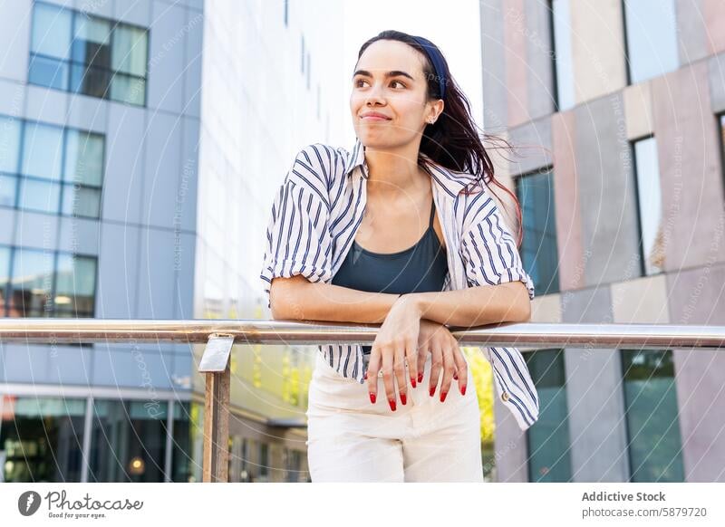 Woman enjoying a bright spring day in the city woman portrait urban architecture smile relaxed gentle casual blouse striped railing modern daytime outdoors