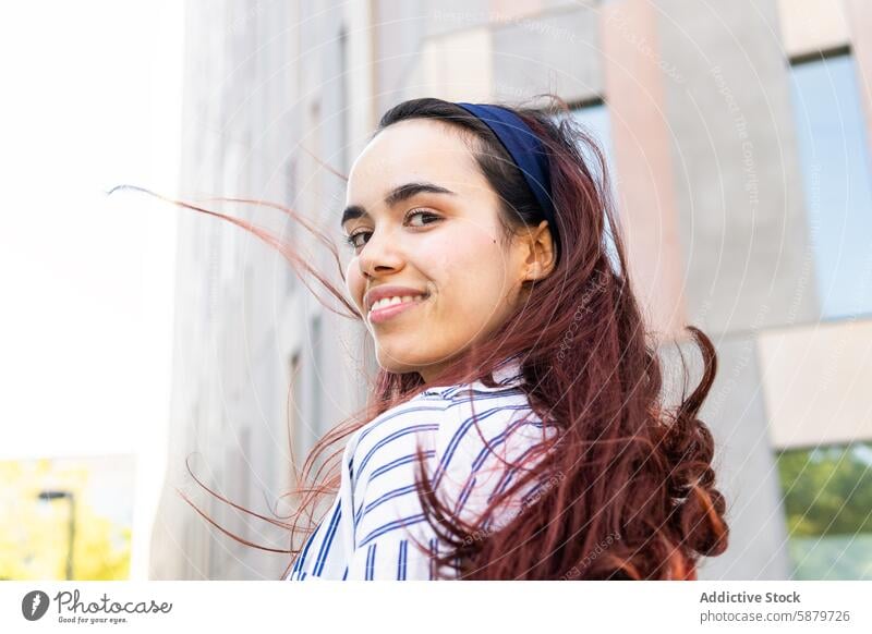 Happy young woman enjoying a sunny spring day outdoors portrait smiling joyful headband casual style hair flowing relaxed cheerful urban afternoon bright