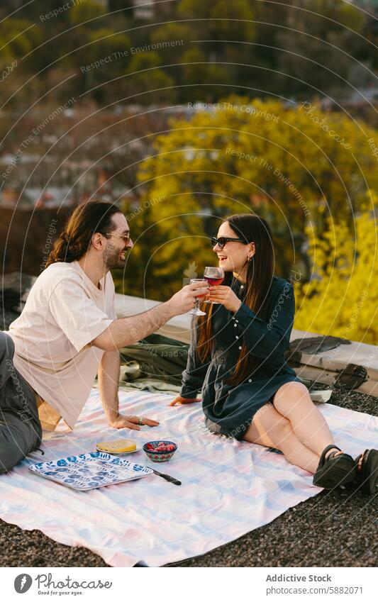 Couple enjoys a sunset picnic on the rooftop couple wine toast romantic woman greenery city view sunshine outdoors leisure relaxation happiness love bonding