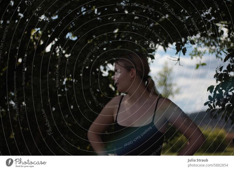 In the shade Shadow Woman Blonde Braids Rainbow tattoo Summer out plants leaves Hedge cooling warm Sunglasses