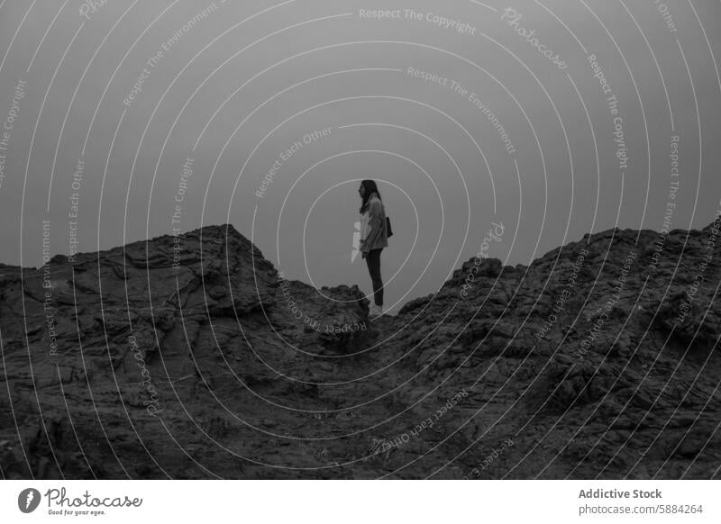 Lone figure stands atop rocky landscape near Favaritx Lighthouse woman favaritx lighthouse menorca monochrome serene solitude nature scenic outdoor rugged