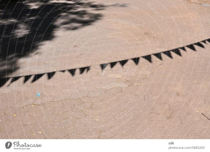 Shadow play of a pennant chain on the paved playground of a school. Paper chain Decoration Feasts & Celebrations Party Deserted variegated Multicoloured