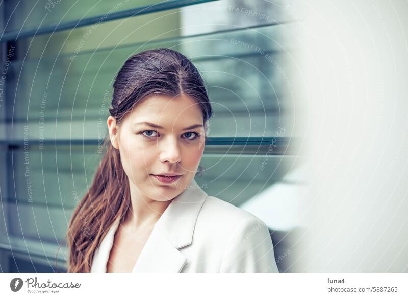 Self-confident young woman in front of a glass facade Woman relaxed Young woman Meditative sensual Dreamily portrait fortunate youthful Happy Single optimistic