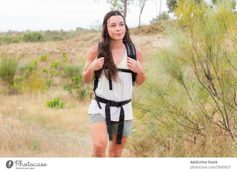 Woman hiking through the countryside with a backpack woman outdoor activity lifestyle dry landscape young long hair adventure summer nature travel trek explorer