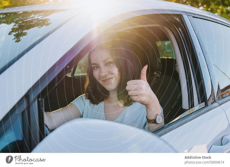 Young woman giving thumbs up from her car driver smile gesture seat satisfaction safety sunny day female young vehicle transport driving positive happy cheerful