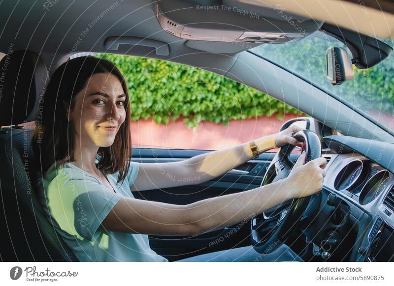 Young woman smiling while driving her car driver vehicle steering wheel smile happy seat interior road journey travel transportation safety secure grip control