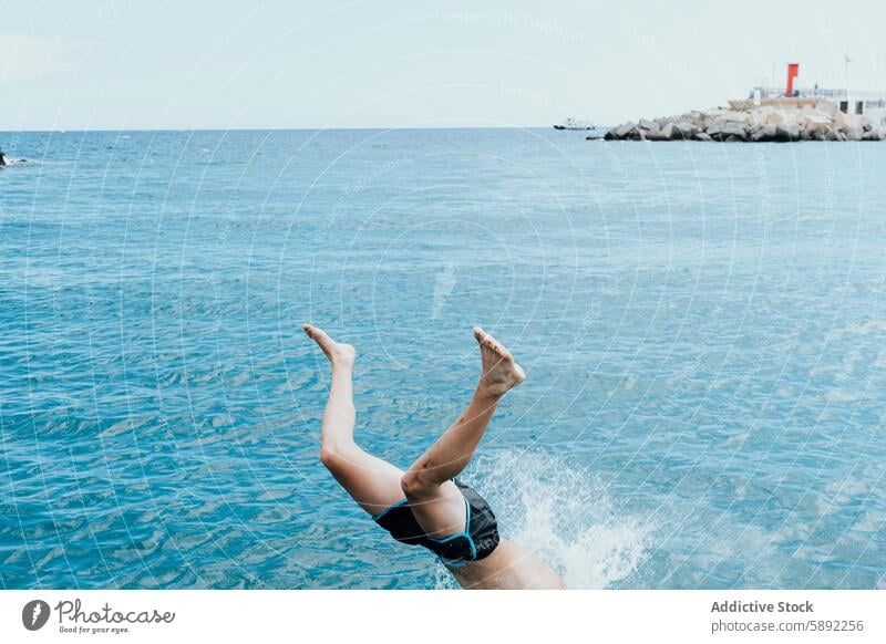 A person happily dives into the blue sea during summer vacation holiday man splash water clear sky serene coast coastal scene spirit swimming trunk joy freedom