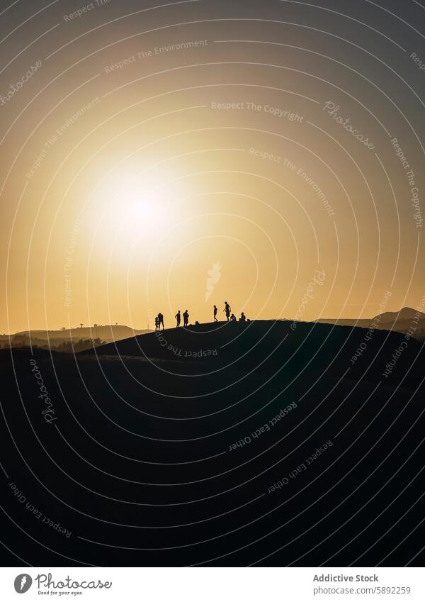 Silhouettes of people walking at sunset in summer silhouette hill evening outdoor adventure travel leisure holiday nature landscape warm scenic sky golden hour