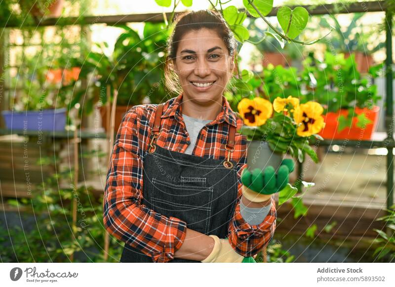 Happy woman with flower in hand greenhouse potted smile positive happy plant botany flora female gardener hothouse viola tricolor horticulture growth cheerful