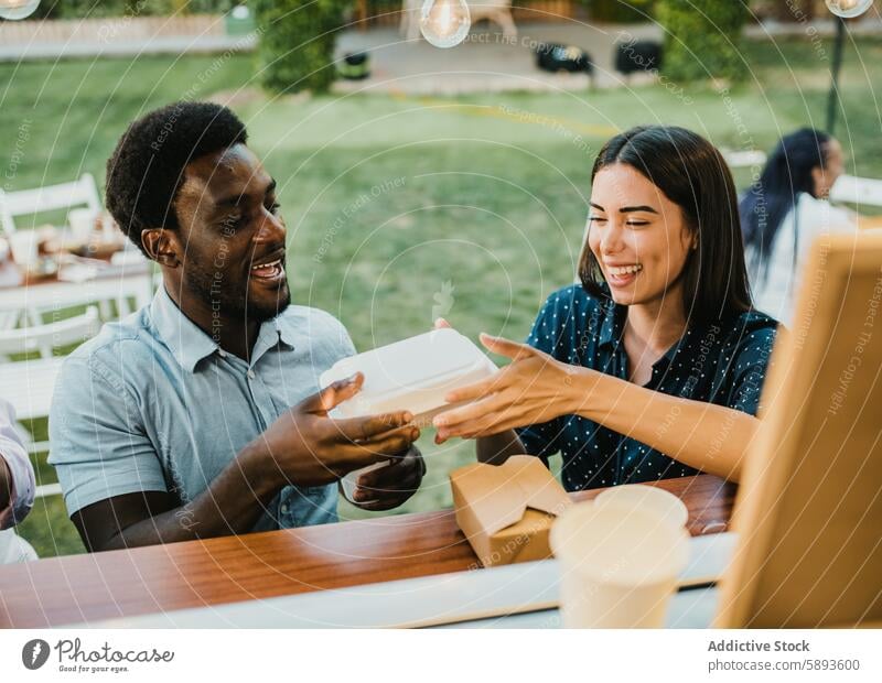 Diverse couple receiving takeaway order in food truck smile box carry park happy man woman dish to go lunch service meal together diverse multiethnic