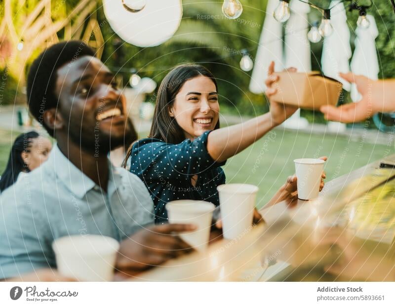 Cheerful woman taking takeaway food near black man order truck park cheerful box seller client smile weekend customer to go purchase street food happy optimist