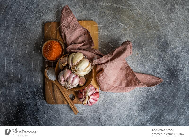 Rustic garlic and spices on cutting board in kitchen wooden rustic linen cloth warm textured composition background gray whole bulb fresh aromatic cooking