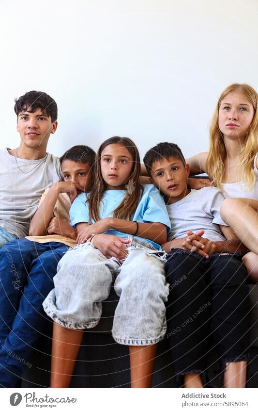 Triplets with siblings on a couch triplet boy girl group portrait casual comfortable bond sitting indoor family brother sister youth neutral expression together