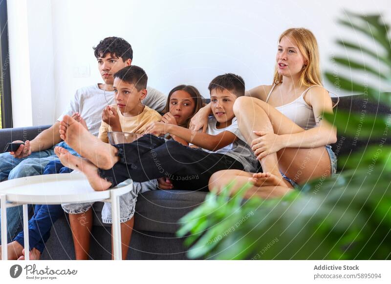 Triplets and family enjoying a movie on a couch triplet sofa watching relaxing home casual comfortable room well-lit indoor leisure bond togetherness