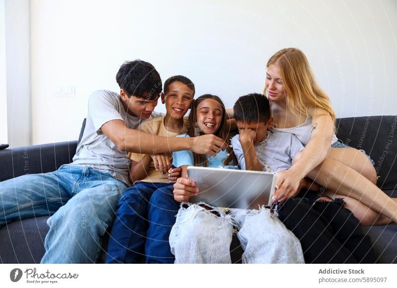 Family of five enjoying time together with a tablet family mother triplet couch digital bonding interaction cozy fun indoor technology home living room comfort