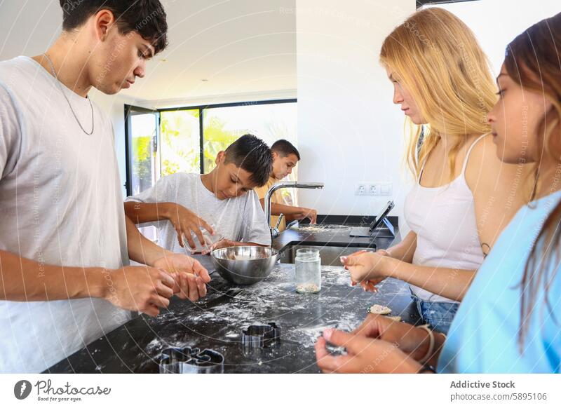 Triplets baking cookies together in kitchen with their siblings triplet brother sister cooking dough cookie cutter preparation homemade casual wear modern