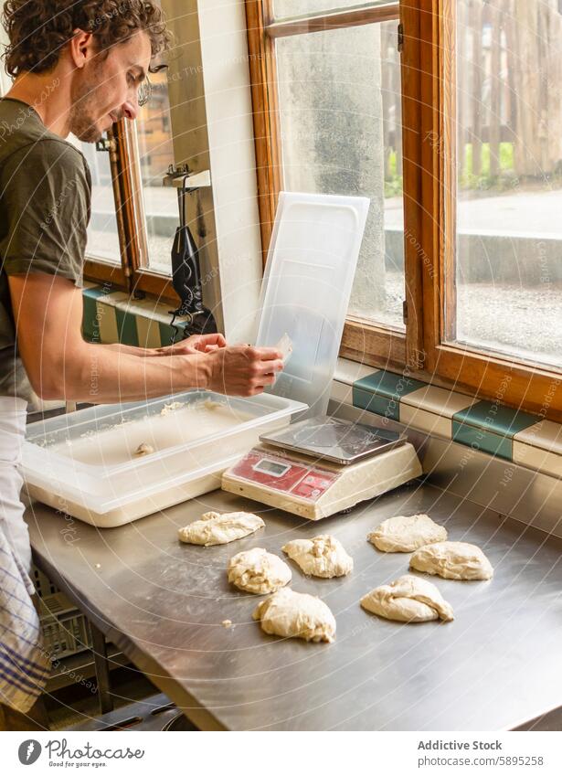 Baker preparing dough in a kitchen with garden view baker pizza scale window sunlight rustic quality meticulous portion digital consistency preparation baking