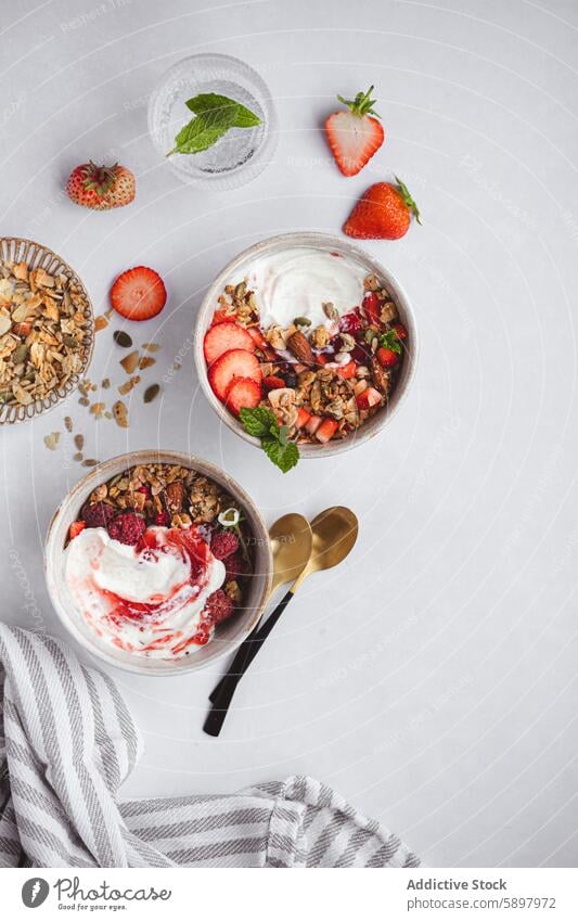 Top view of summer healthy breakfast with yogurt and granola strawberry raspberry almond mint nutritious light background bowl fresh fruit dairy meal morning