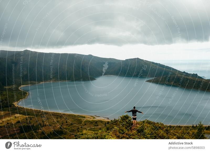 Man enjoying panoramic view of a lake in Sao Miguel, Azores. sao miguel azores man mountains solitude nature lush hilltop serene water landscape travel outdoor