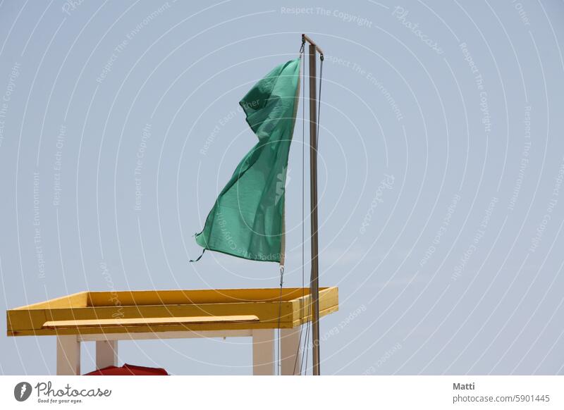 Green flag at the lifeguard station Flag be afloat Beach Sand Lifeguard Hunting Blind Sky Swimming allowed Ocean Swimming & Bathing Waves