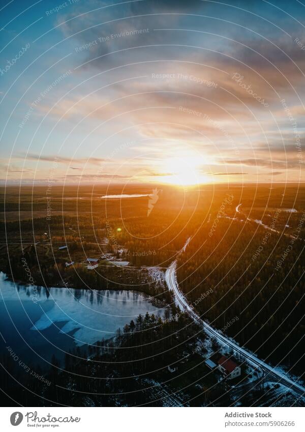 Aerial view of a sunset in Lapland over a frozen lake and forest lapland aerial view road landscape beauty nature winter evening natural light serenity