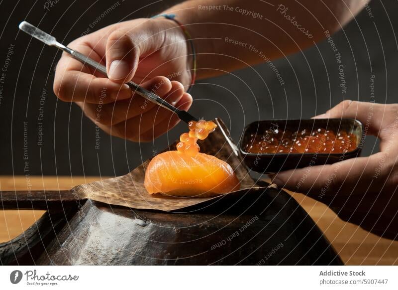 Delicate preparation of sushi with caviar topping chef salmon garnish tool technique presentation flavor cuisine japanese food seafood delicacy gourmet