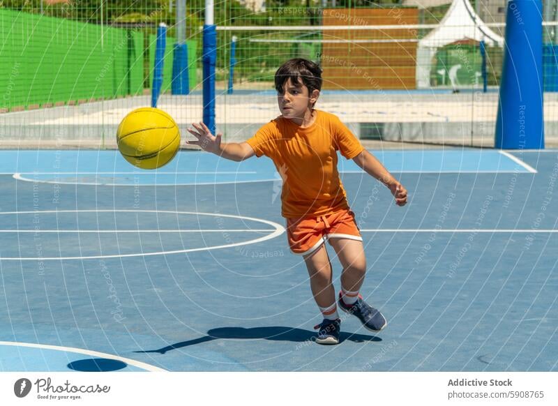 Young boy in motion playing basketball outdoors child sport court game action active youth sportswear sunny daylight physical healthy lifestyle energy focus